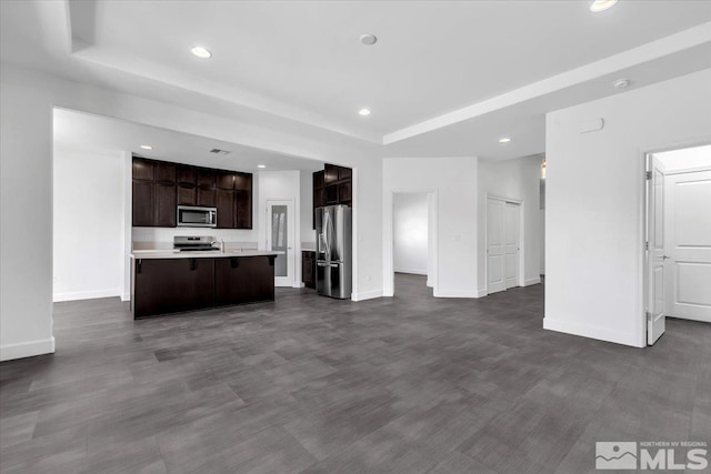 unfurnished living room with recessed lighting, a tray ceiling, and baseboards