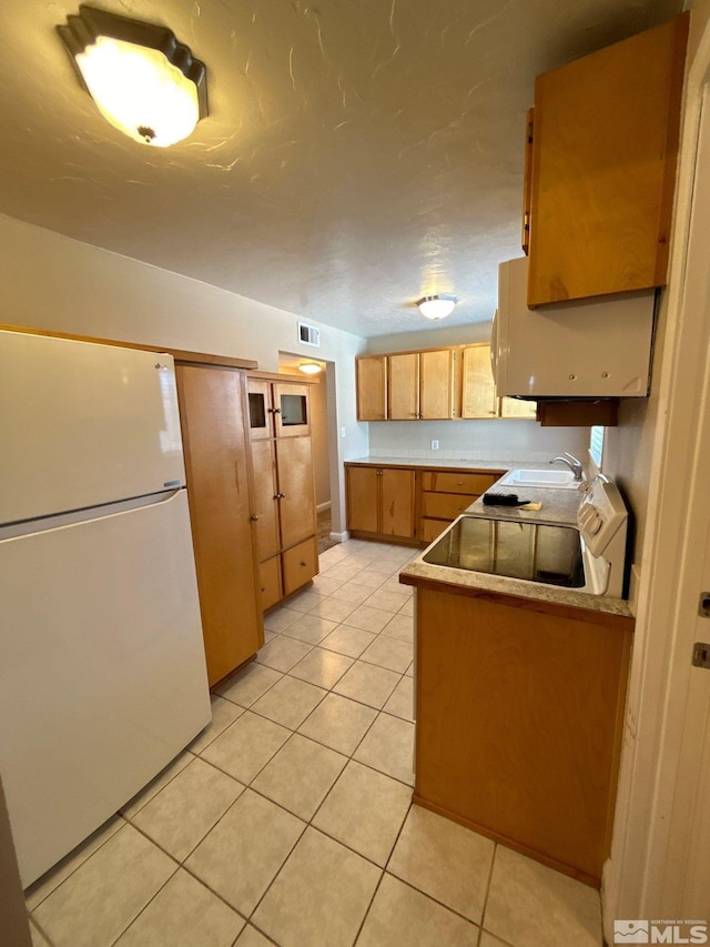 kitchen with visible vents, light countertops, light tile patterned floors, freestanding refrigerator, and a sink