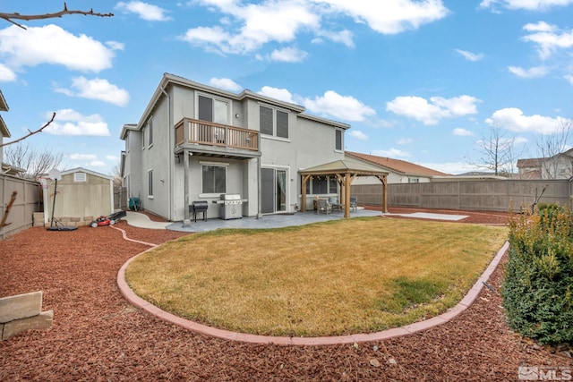 back of property featuring a fenced backyard, a balcony, a gazebo, a storage unit, and a patio area