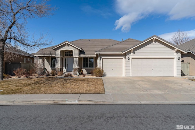 view of front of home with concrete driveway, an attached garage, a front yard, fence, and a tiled roof