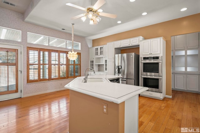 kitchen featuring stainless steel appliances, white cabinetry, light countertops, and a sink