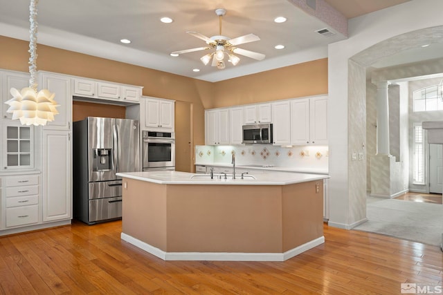 kitchen featuring white cabinets, an island with sink, stainless steel appliances, light countertops, and a sink