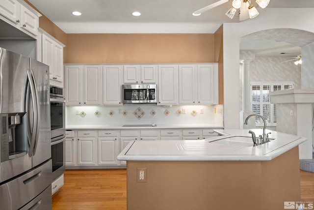 kitchen featuring stainless steel appliances, light countertops, a sink, and white cabinetry