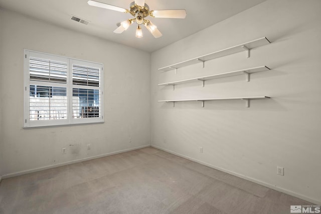 unfurnished room with a ceiling fan, light colored carpet, visible vents, and baseboards