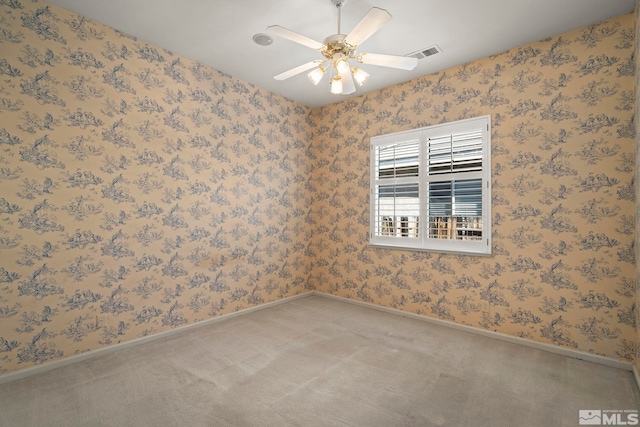 carpeted spare room with visible vents, ceiling fan, baseboards, and wallpapered walls