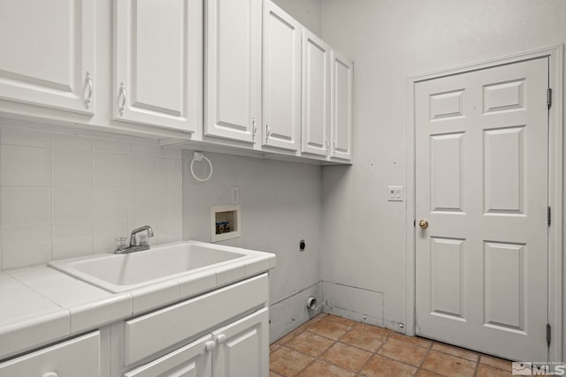 washroom featuring cabinet space, stone finish floor, electric dryer hookup, washer hookup, and a sink