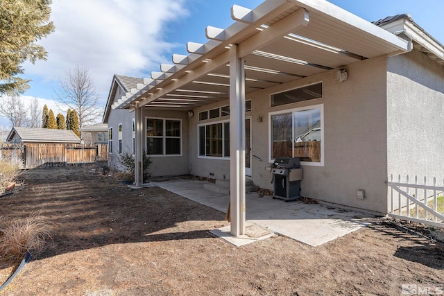 rear view of property featuring a patio area, fence, and stucco siding