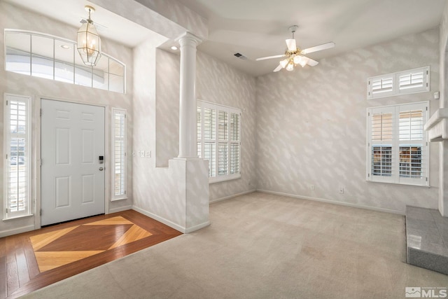 entryway featuring decorative columns, carpet flooring, ceiling fan, baseboards, and wallpapered walls