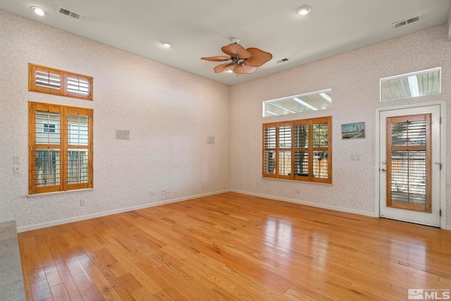 empty room featuring light wood finished floors, baseboards, and visible vents