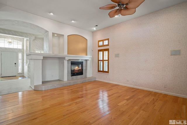 unfurnished living room featuring baseboards, a fireplace, light wood finished floors, and ceiling fan