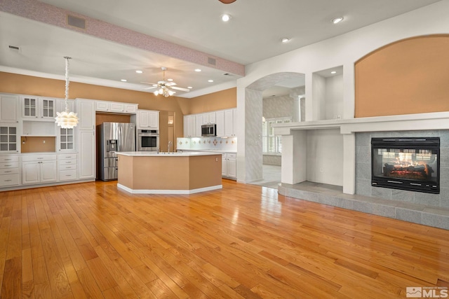 kitchen featuring stainless steel appliances, hanging light fixtures, open floor plan, white cabinets, and a kitchen island