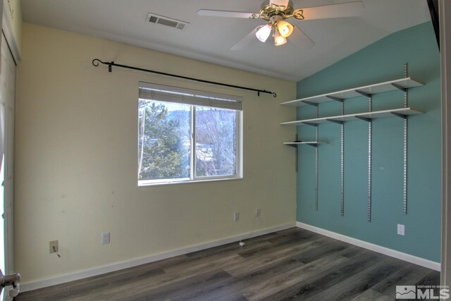 empty room with lofted ceiling, visible vents, dark wood finished floors, and baseboards