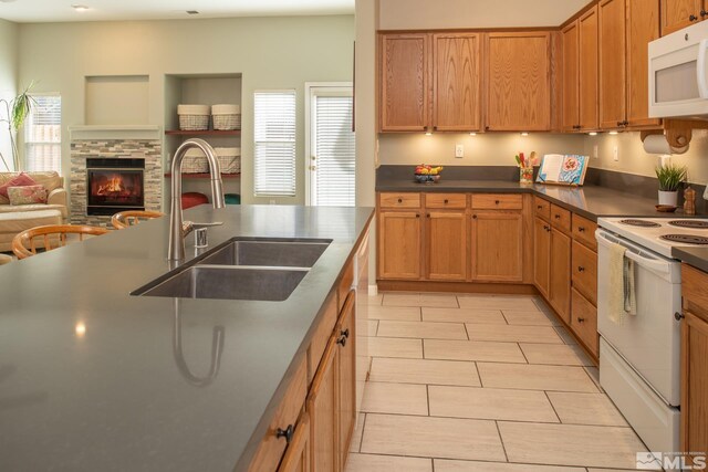 kitchen with dark countertops, open floor plan, a sink, white appliances, and plenty of natural light