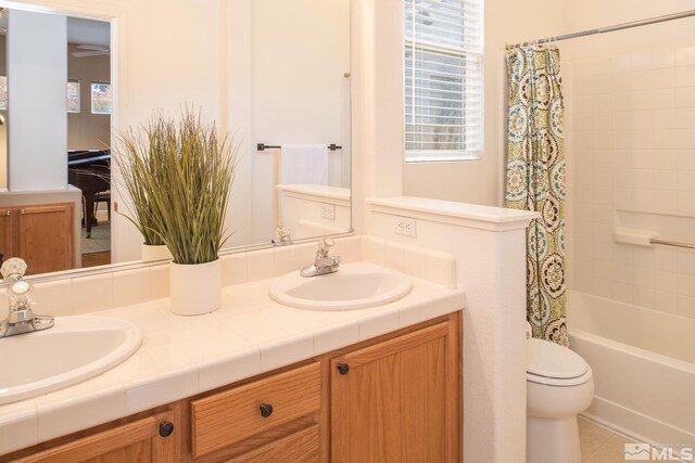 bathroom with double vanity, a sink, toilet, and shower / tub combo with curtain