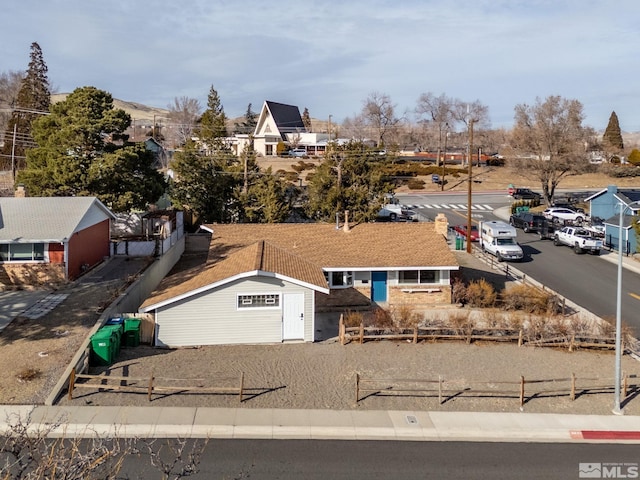 view of front of home with a residential view and fence