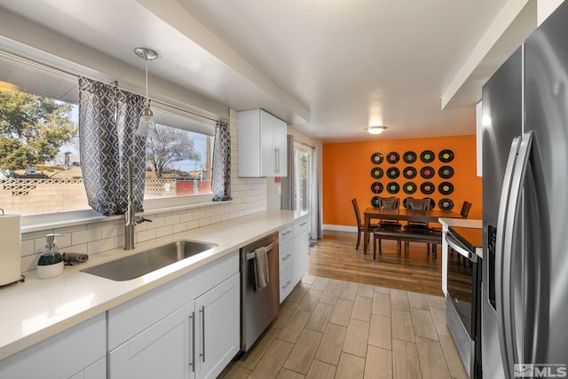 kitchen with white cabinets, hanging light fixtures, wood tiled floor, stainless steel appliances, and light countertops