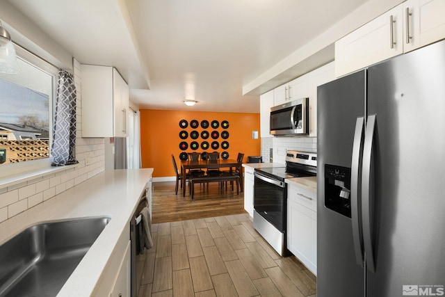 kitchen with white cabinets, wood tiled floor, appliances with stainless steel finishes, and light countertops