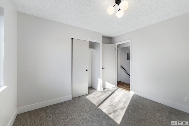 unfurnished bedroom with a textured ceiling, carpet floors, and a closet