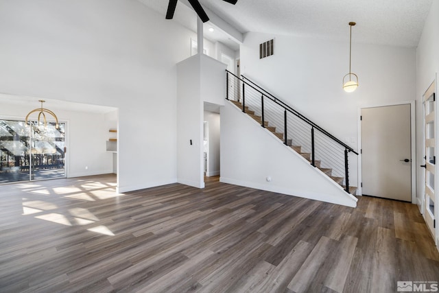 unfurnished living room with dark wood-style floors, visible vents, ceiling fan, baseboards, and stairs