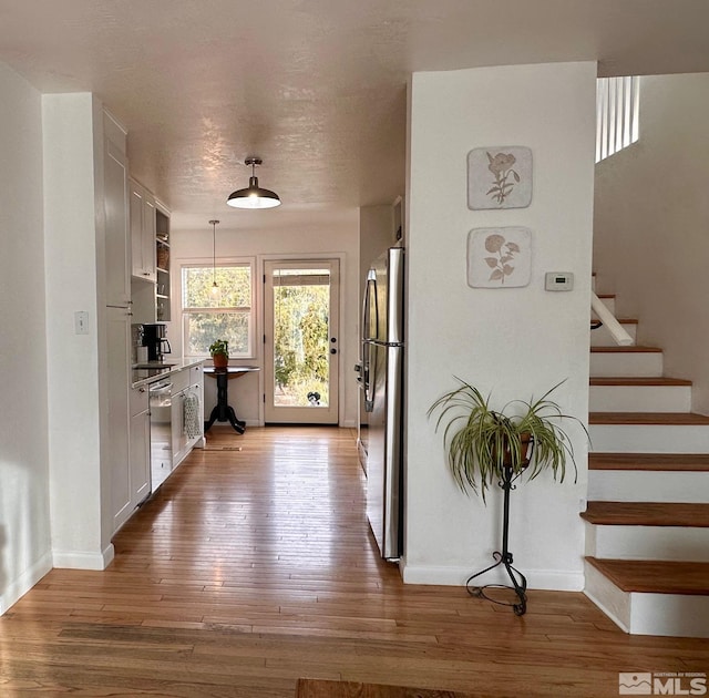 interior space with light wood-style flooring, stairs, baseboards, and a textured ceiling