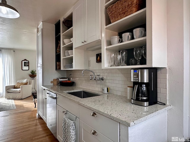 kitchen with open shelves, light stone counters, and a sink