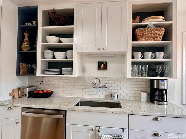 kitchen with light stone counters, open shelves, stainless steel dishwasher, white cabinets, and a sink