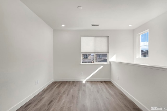 empty room featuring light wood-style floors, baseboards, visible vents, and recessed lighting