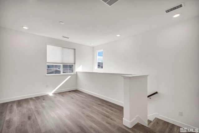 spare room featuring wood finished floors, visible vents, and baseboards