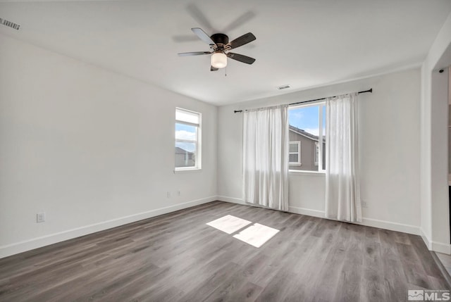 empty room with a healthy amount of sunlight, baseboards, and wood finished floors