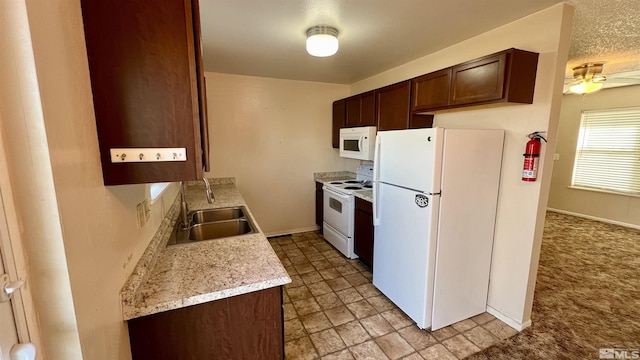 kitchen featuring a ceiling fan, dark brown cabinetry, a sink, white appliances, and baseboards