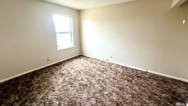 unfurnished room featuring a textured ceiling, carpet, and baseboards