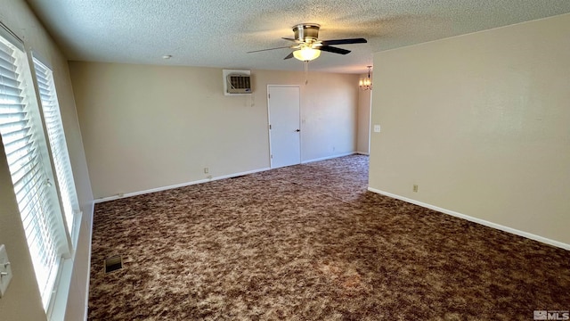 carpeted spare room featuring a wall unit AC, visible vents, ceiling fan, a textured ceiling, and baseboards