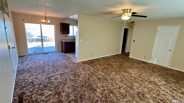 unfurnished living room featuring carpet, a textured ceiling, baseboards, and ceiling fan with notable chandelier