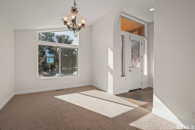 entryway with visible vents, arched walkways, dark colored carpet, and baseboards