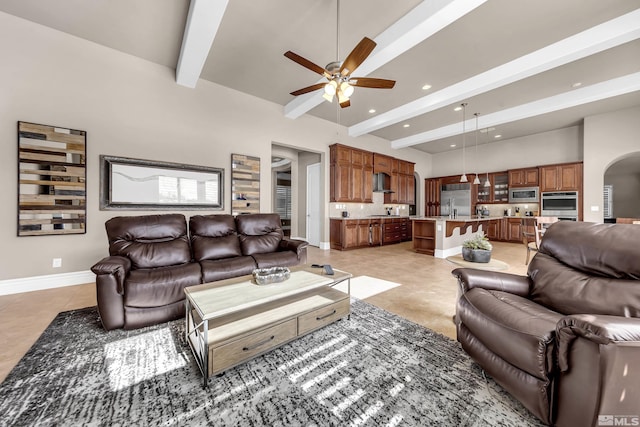 living area with arched walkways, recessed lighting, a towering ceiling, beamed ceiling, and baseboards