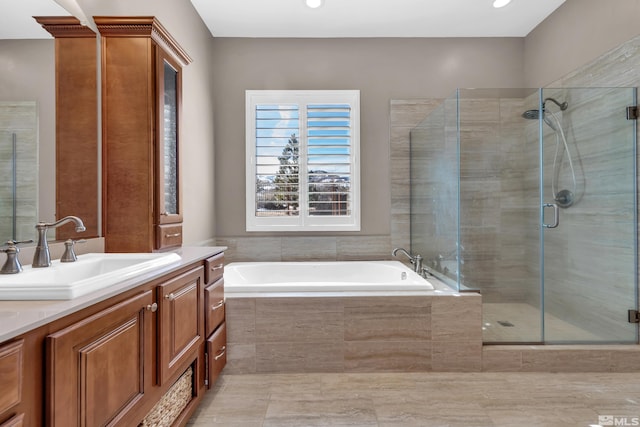 bathroom featuring a stall shower, a bath, and vanity