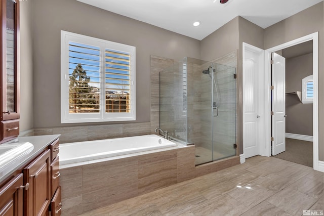 bathroom with baseboards, a garden tub, vanity, and a shower stall