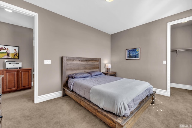 bedroom featuring a walk in closet, a closet, light colored carpet, and baseboards