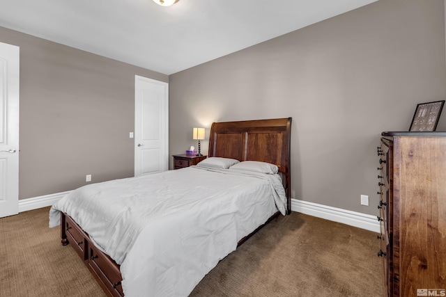 bedroom with dark colored carpet and baseboards