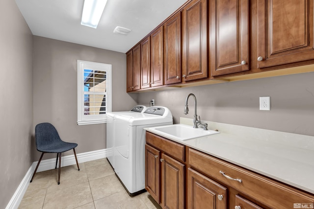 laundry area with washer and clothes dryer, cabinet space, light tile patterned flooring, a sink, and baseboards