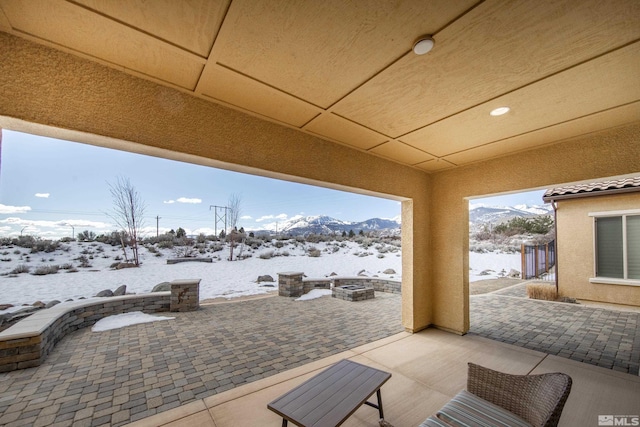 snow covered patio featuring an outdoor fire pit and a mountain view