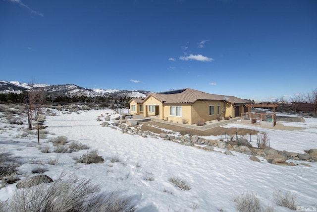 view of front of home featuring a tile roof, a mountain view, and stucco siding