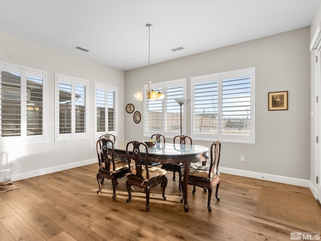 dining area featuring an inviting chandelier, wood finished floors, visible vents, and baseboards