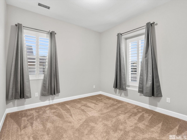 carpeted empty room featuring visible vents and baseboards