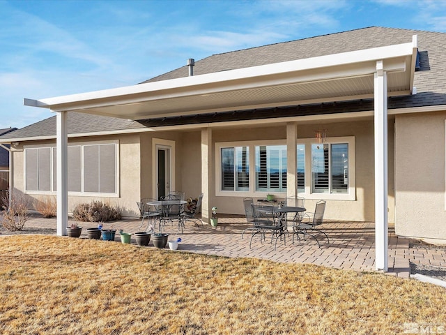 back of property featuring a patio area, a shingled roof, a lawn, and stucco siding