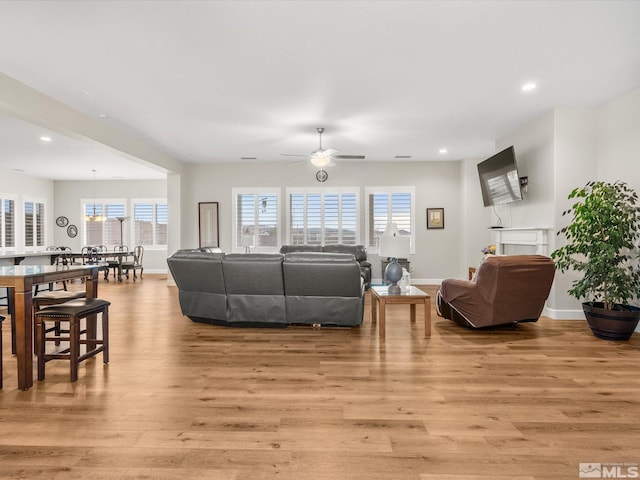 living area featuring light wood-style flooring, baseboards, a ceiling fan, and recessed lighting