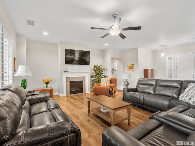 living room with baseboards, a tile fireplace, ceiling fan, light wood-style floors, and recessed lighting