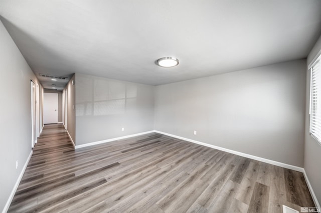 spare room with light wood-type flooring, visible vents, and baseboards