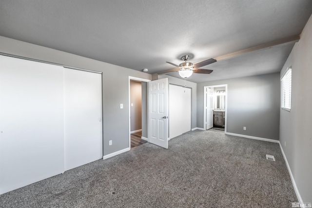 unfurnished bedroom with two closets, dark colored carpet, visible vents, a ceiling fan, and baseboards