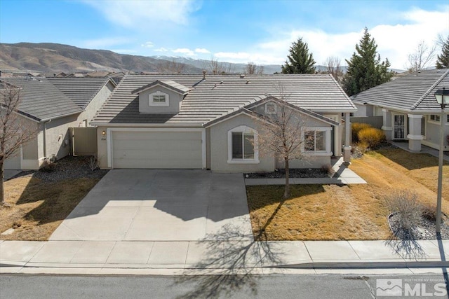 view of front of home with concrete driveway, a tile roof, an attached garage, a mountain view, and stucco siding